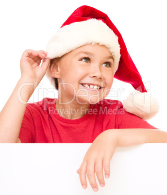 Little girl in santa hat is holding blank board