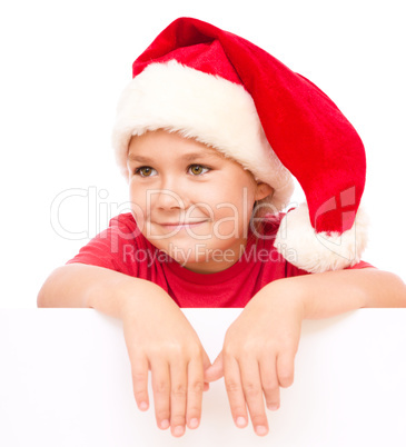 Little girl in santa hat is holding blank board