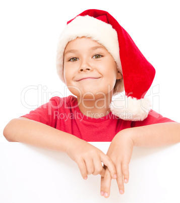 Little girl in santa hat is holding blank board