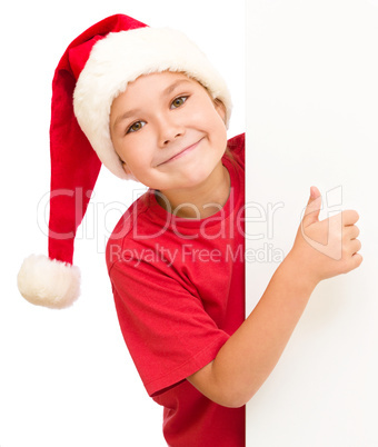 Little girl in santa hat is holding blank board