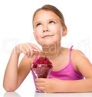 Happy little girl is eating raspberries