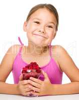 Happy little girl is eating raspberries