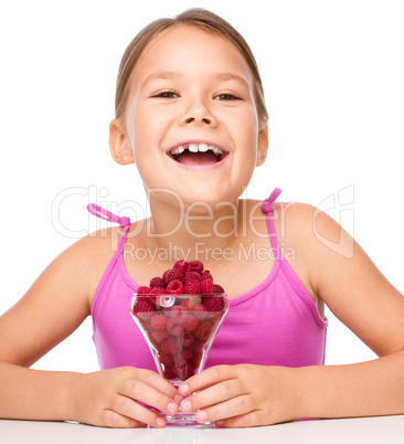 Happy little girl is eating raspberries