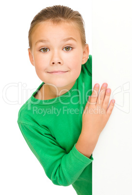 Little girl is looking from out blank board