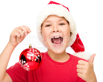 Little girl in santa hat is showing thumb up sign