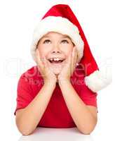 Little girl in santa hat is daydreaming