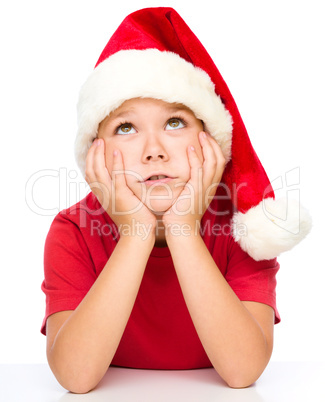 Little girl in santa hat is daydreaming