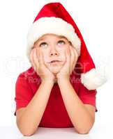 Little girl in santa hat is daydreaming