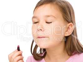 Little girl is applying lipstick