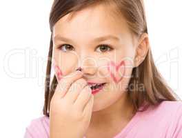 Little girl is applying lipstick on her nose