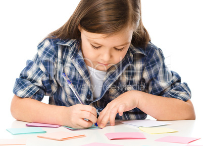 Girl is writing on color stickers using pen