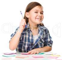 Girl is writing on color stickers using pen