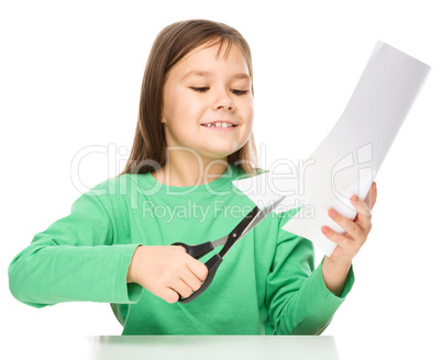 Little girl is cutting paper using scissors