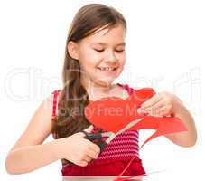 Portrait of a little girl cutting out red heart
