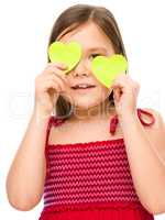 Little girl is holding hearts over her eyes