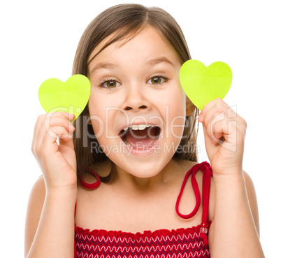 Little girl is holding hearts near her eyes