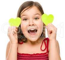 Little girl is holding hearts near her eyes