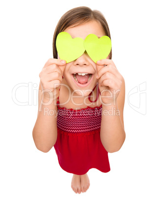 Little girl is holding hearts over her eyes