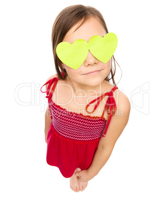 Little girl is holding hearts over her eyes