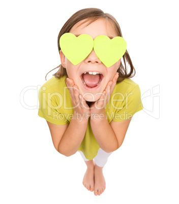 Little girl is holding hearts over her eyes