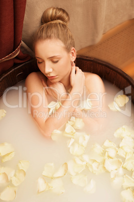 Lovely woman enjoys relaxing bath with rose petals
