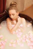 Spa. Girl takes bath with sea salt and rose petals