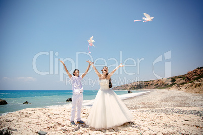 Happy smiling bride and groom hands releasing white doves on a sunny day.  Mediterranean Sea. Cyprus