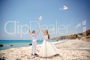 Happy smiling bride and groom hands releasing white doves on a sunny day.  Mediterranean Sea. Cyprus