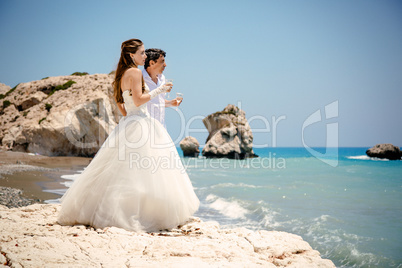 bride and groom with glasses of champagne on the beach Mediterranean Sea