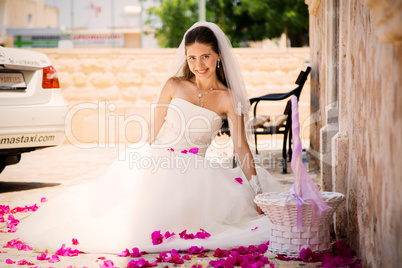 pretty young girl in a wedding dress sitting rose petals