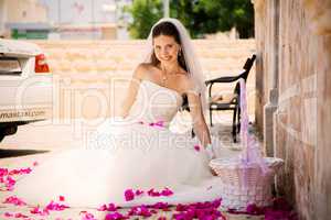 pretty young girl in a wedding dress sitting rose petals