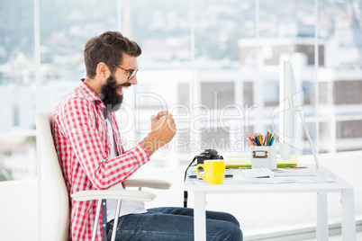 Hipster man sitting at computer desk is happy