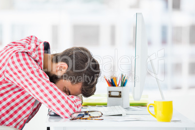 Hipster man sitting at computer desk is tired