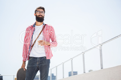 Hipster man holding his skateboard