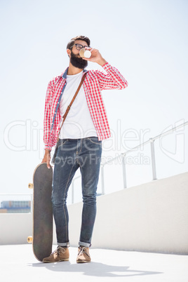 Hipster man holding his skateboard