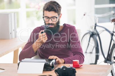 Hipster man using a typewriter and smoking the pipe