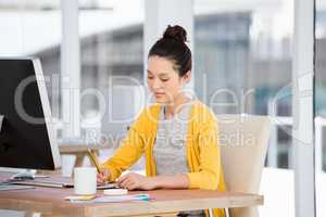 A working girl is writing at her desk