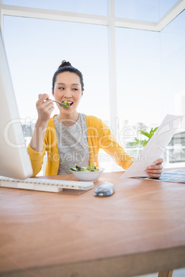 A beautiful businesswoman eating and reading