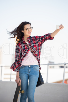 Hipster with skateboard taking pictures