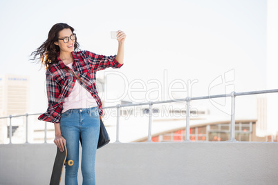 Hipster with skateboard taking pictures