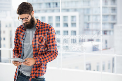 Hipster is using tablet and standing