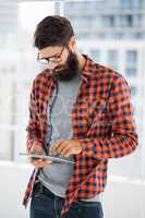 Hipster is using tablet and standing
