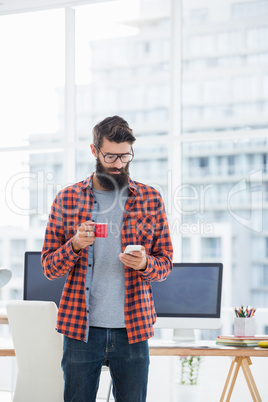 Hipster using smartphone and drinking coffee