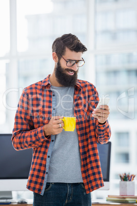 Hipster using smartphone and drinking coffee