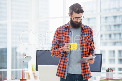 Hipster using tablet and drinking coffee