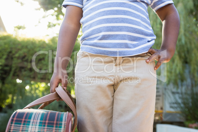 Child with hand on hips holding a bag