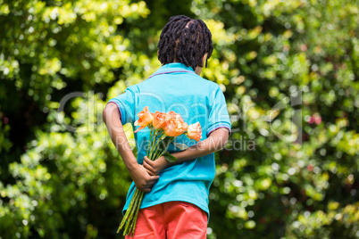 A kid hiding bouquet behind back