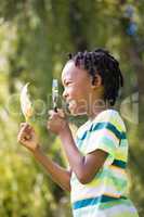 Profile view of boy looking at leaf through magnifying glass