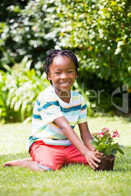 A boy sitting in the grass with plant