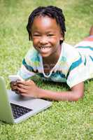 Portrait of kid smiling with a mobile phone and laptop